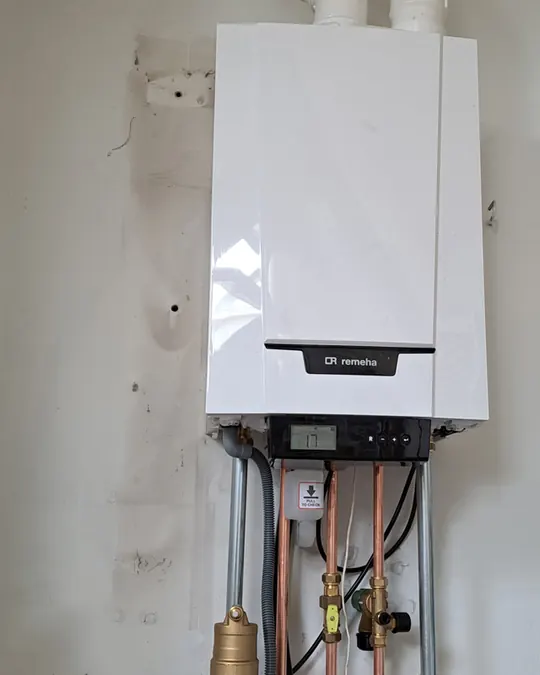 Cv-ketel met koperen aansluitleidingen aan de muur
